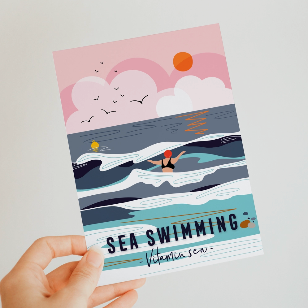 Hand holding a book titled 'Sea Swimming' with a beach illustration on the cover.